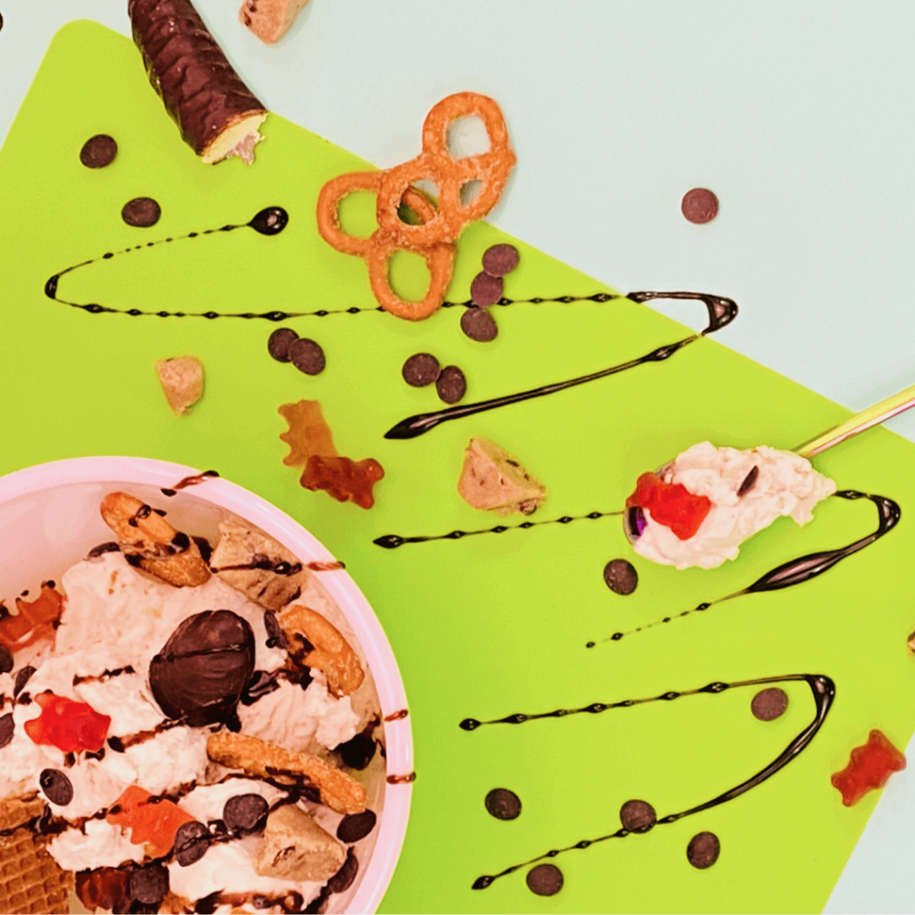ice cream with chocolate drizzle topped with gummy bears and pretzels