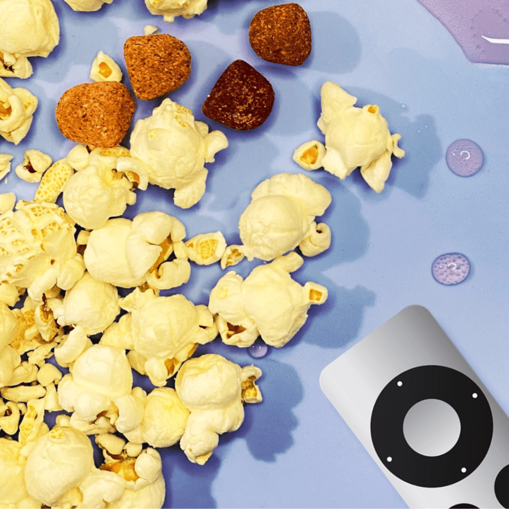 popcorn spilled on the table next to apple tv controller