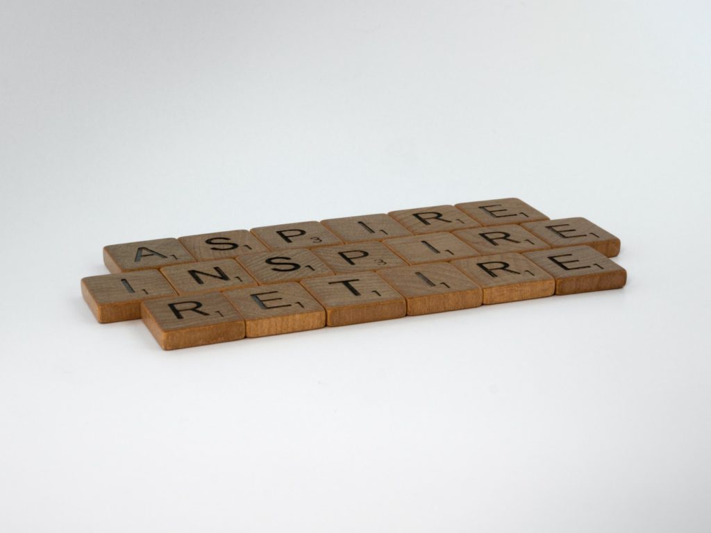 Scrabble tiles arranged to say aspire, inspire, and retire.