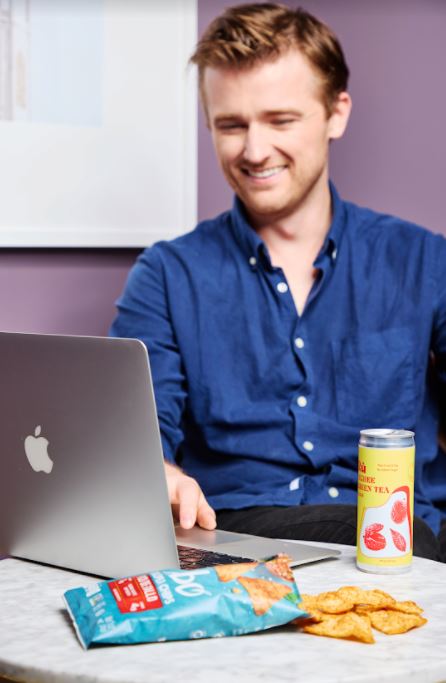 Man eating snacks while watching his laptop