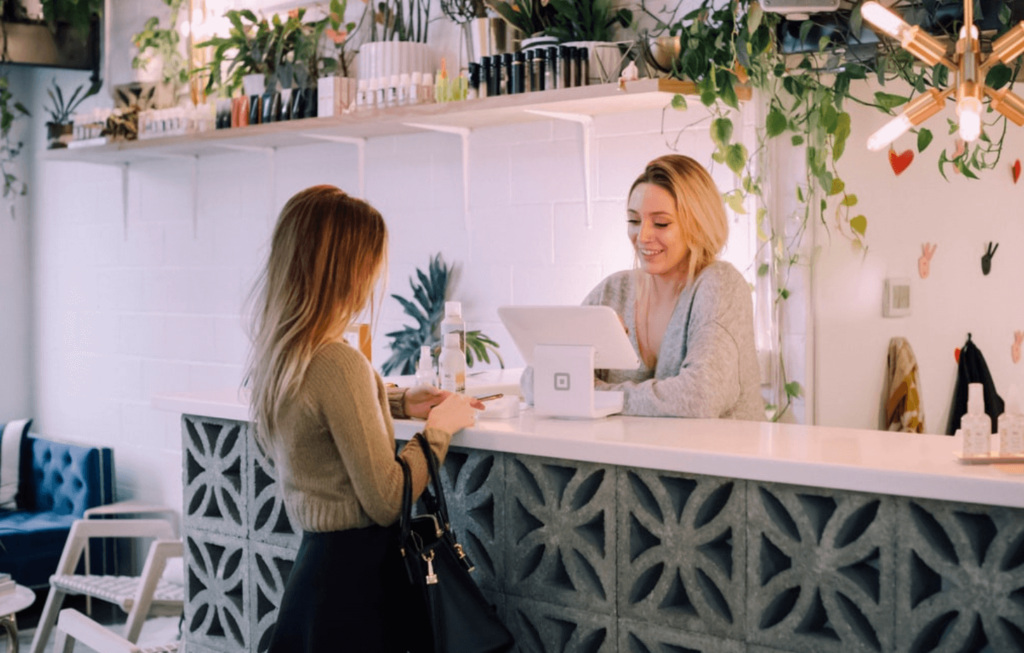 A customer making a purchase in a trendy cafe full of greenery.