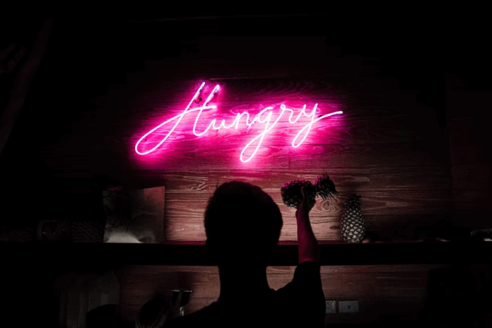 A neon sign in a dark bar, spelling out 