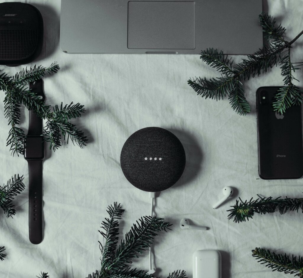 A festive display of evergreen with AirPods and speakers.