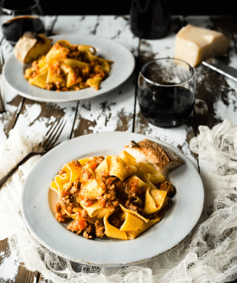 A dinner table with fresh pasta and wine.