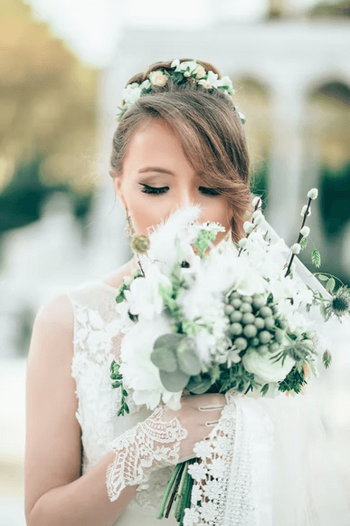 A beautiful bride on her wedding day smelling her bouquet of flowers.