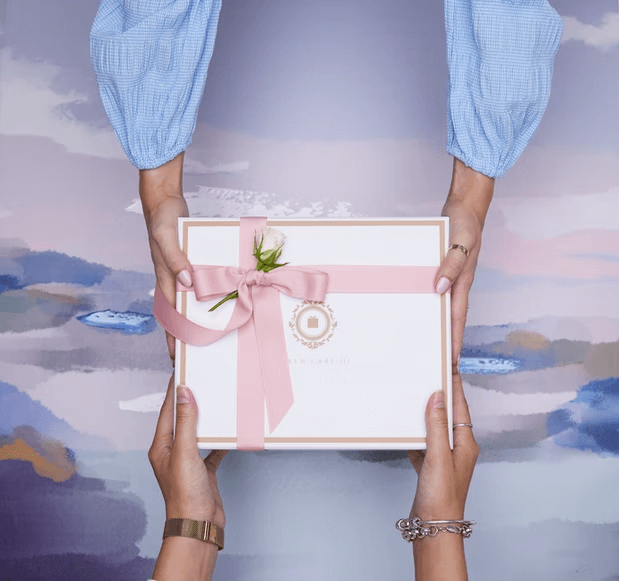 Two women exchanging a gifting box.
