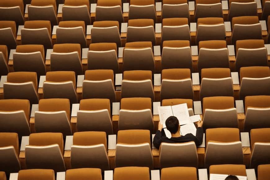 A student in a large lecture hall taking a test. 