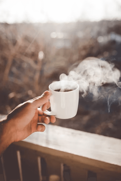 A warm mug of coffee with a plume of steam. 