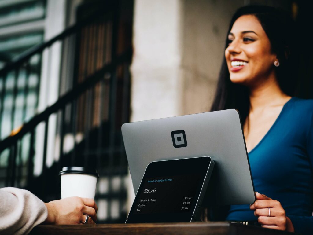 A smiling customer service representative using point of sale software to complete a customers purchase.